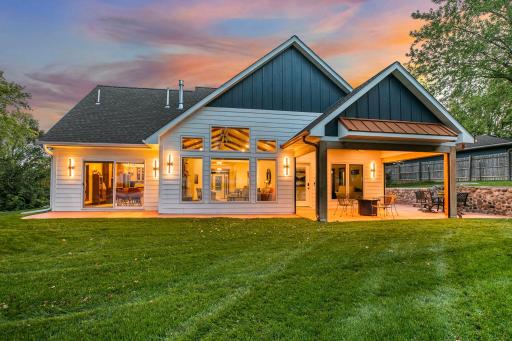 View looking from the lakeside into the house showcases the expansive design of striking custom floor to ceiling windows that anchors the heart of the home, showcasing the open-concept living room.
