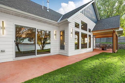 The lakeside showcases a striking contemporary farmhouse aesthetic, seamlessly combining crisp white vertical and horizontal siding with bold navy accents. 8FT sliding door from dining area leads to patio.