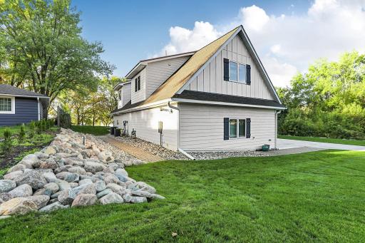 Rear exterior showcases a pristine white facade accented with stricking dark window shutters and premium gable detailing. *New landscape stones were pounded into the ground to secure their location.