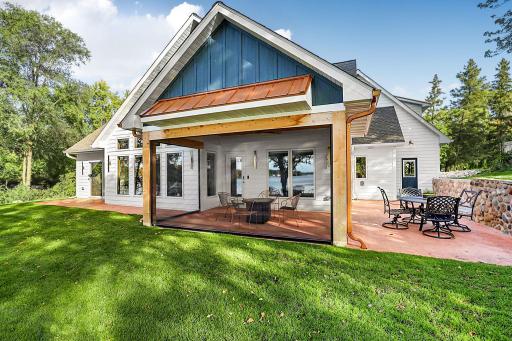 The heart of the outdoor entertainment space centers around an expansive custom-colored concrete patio. Featuring premium exposed wood beans and sleek standing-seam metal accent roof and cooper rain gutters and downspouts.
