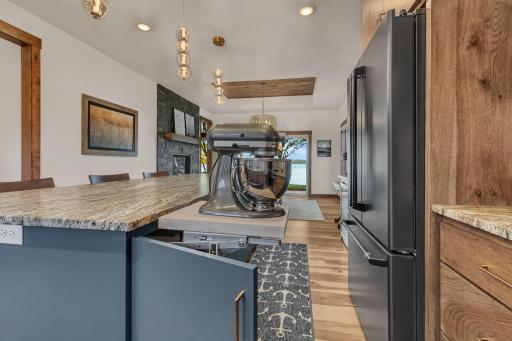 Premium storage solutions, custom wood cabinetry is paired with specialized, space-saving hardware designed to lift and store heavy countertop appliances effortlessly.