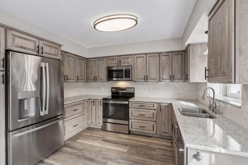 Spacious bright & open kitchen with stainless appliances and custom cabinetry, granite countertops and ceramic tile backsplash.