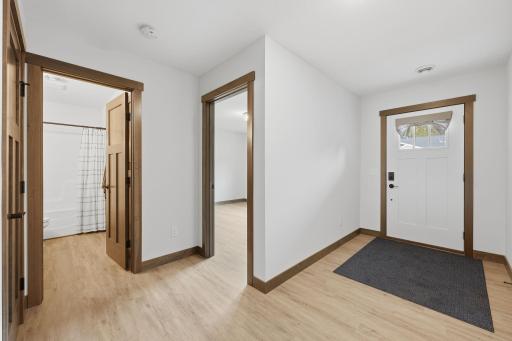 Spacious entry foyer with plank vinyl flooring, 3 panel doors, beautiful woodwork throughout and knockdown ceilings