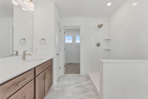 Owner's bathroom with double vanity, tiled shower, and linen closet leading to walk-in closet