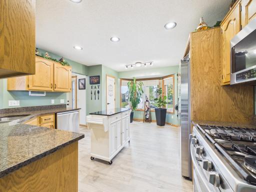 Kitchen with granite countertops, stainless steel appliances, bay window, and adjoining dining area.