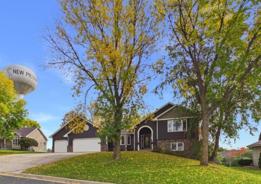 Front exterior with mature trees, lawn, and concrete driveway.