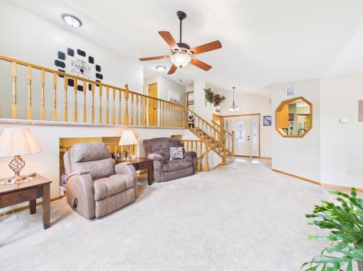 Living room with vaulted ceiling, ceiling fan, and open connection to the dining area.