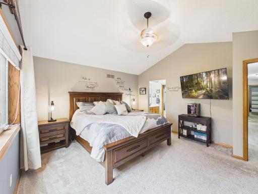 Primary bedroom with window, ceiling fan, and connected suite layout.