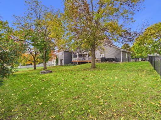 Backyard view showing open lawn space, tree coverage, and the rear of the home.