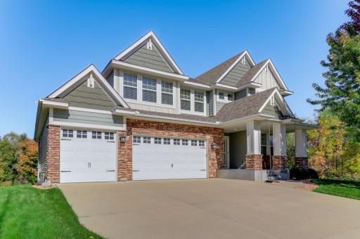 Front exterior highlighting the concrete driveway, three-car garage, stone facade, and beautiful lot.