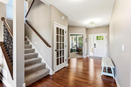 Hardwood floors and a wide entryway introduce the main level, leading directly to a dedicated front office with glass windwo French doors.