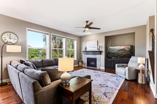 The main living room is anchored by a gas fireplace and framed by large windows that bring in natural light and highlight the pond views.