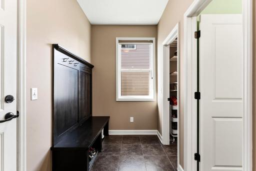 A dedicated mudroom drop zone near the garage entrance includes built-in seating, coat hooks, and durable tile flooring for practical storage.