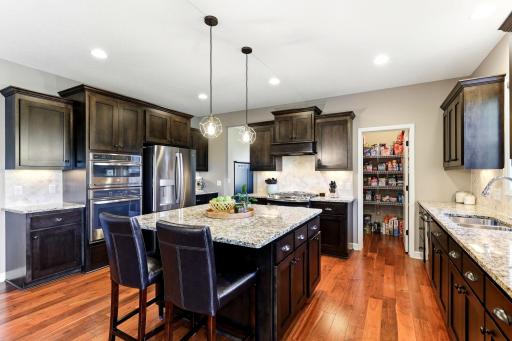 Dark cabinetry and granite countertops provide ample workspace, with convenient access to the adjoining walk-in pantry