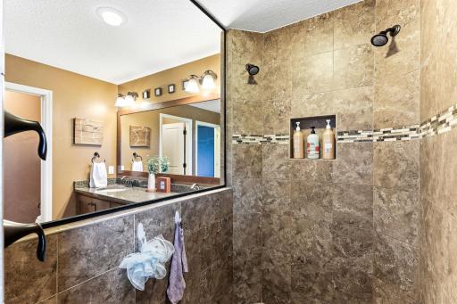 he spa-inspired walk-in shower features premium floor-to-ceiling tile work, dual showerheads, and a built-in niche for streamlined daily routines.