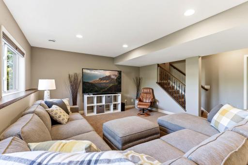This expansive recreation room features plush carpeting, recessed lighting, and large lookout windows that fill the space with natural light.