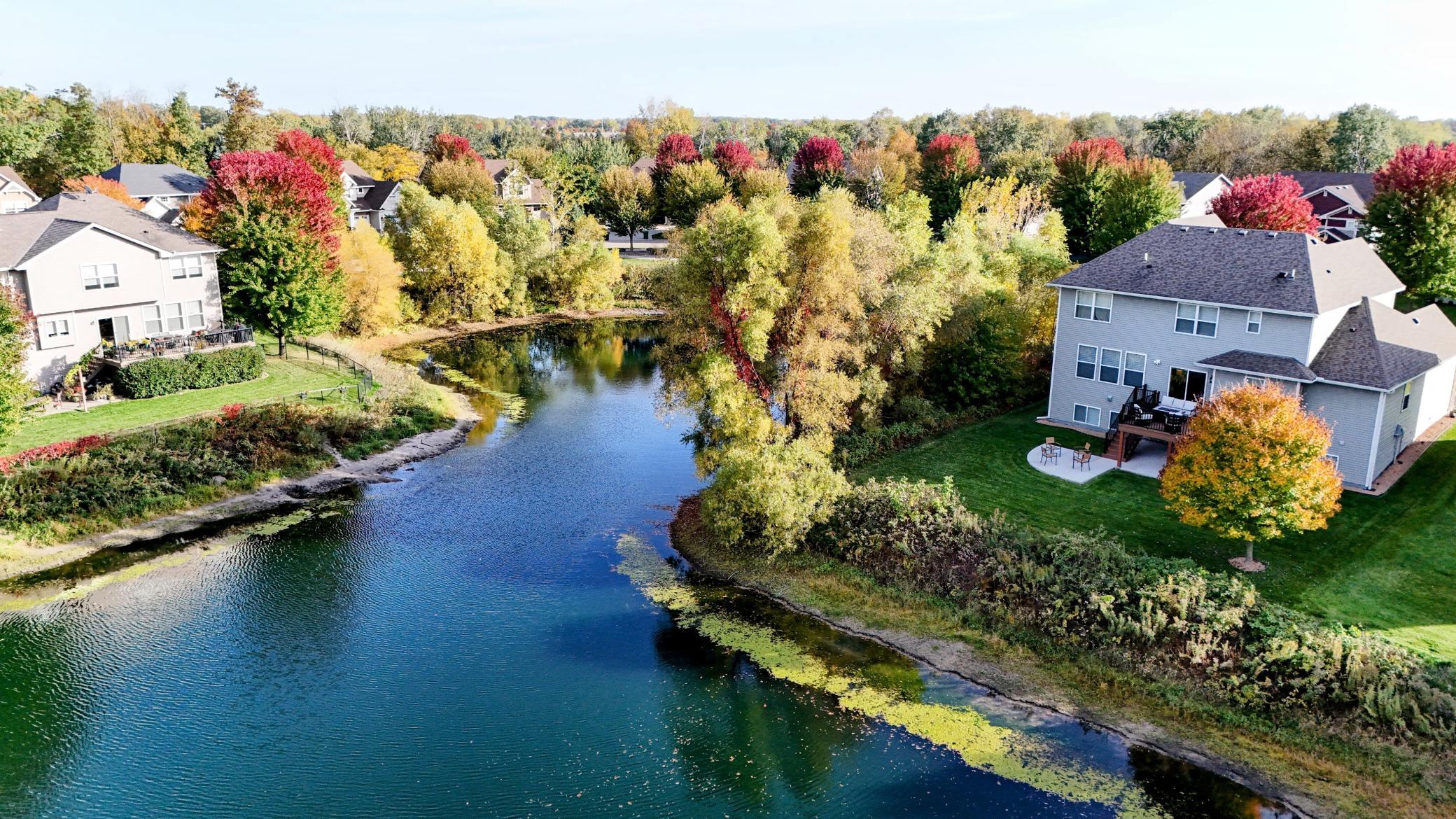 Outdoor living is elevated with a premium Trex deck and custom poured concrete patios seamlessly connecting the home to the tranquil, wrap-around pond.