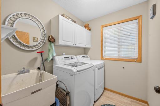 Main-level laundry room with washer, dryer, utility sink, storage cabinets.