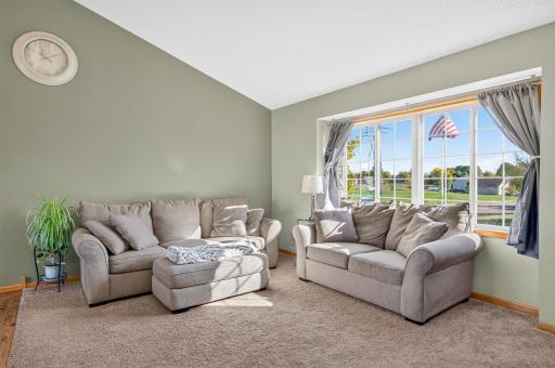 Inviting living room with vaulted ceiling, plush carpeting, and an oversized picture window filling the space with natural light.