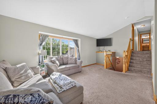 Sun-filled living room with vaulted ceiling and large picture window overlooking the front yard.