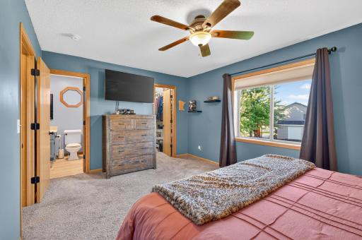 Spacious upper-level primary suite featuring a private bath, walk-in closet, ceiling fan, and abundant natural light.