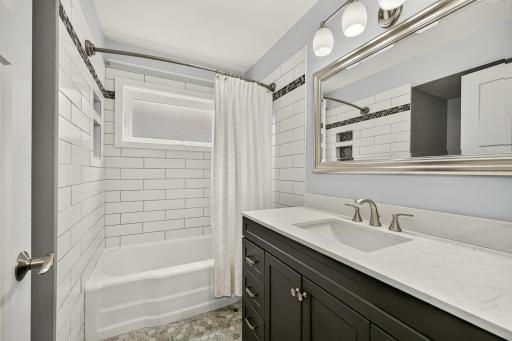 Main floor bath with HEATED ceramic tile flooring! Classy tile tub/shower surround with niches. New large vanity and great lighting!