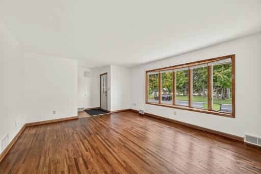 Front entryway opens to a spacious and well-lit living room featuring hardwood flooring.