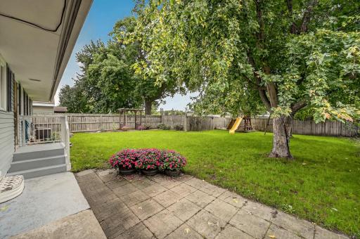 Back patio and fenced yard with mature trees.