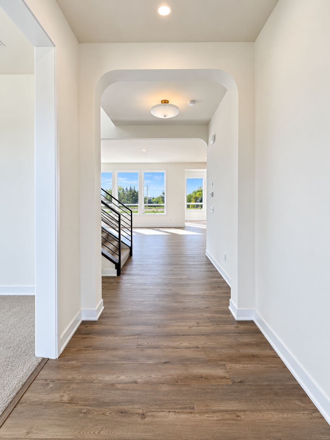 Welcoming entry with warm wood flooring, architectural archways, and a beautiful sightline into the light-filled main living area.