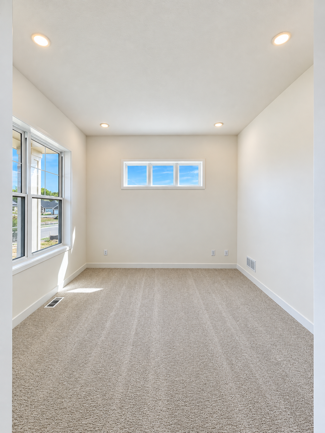 Bright main-level flex room with large windows, additional transom windows, recessed lighting, and plenty of space for a home office, den, or additional living area.