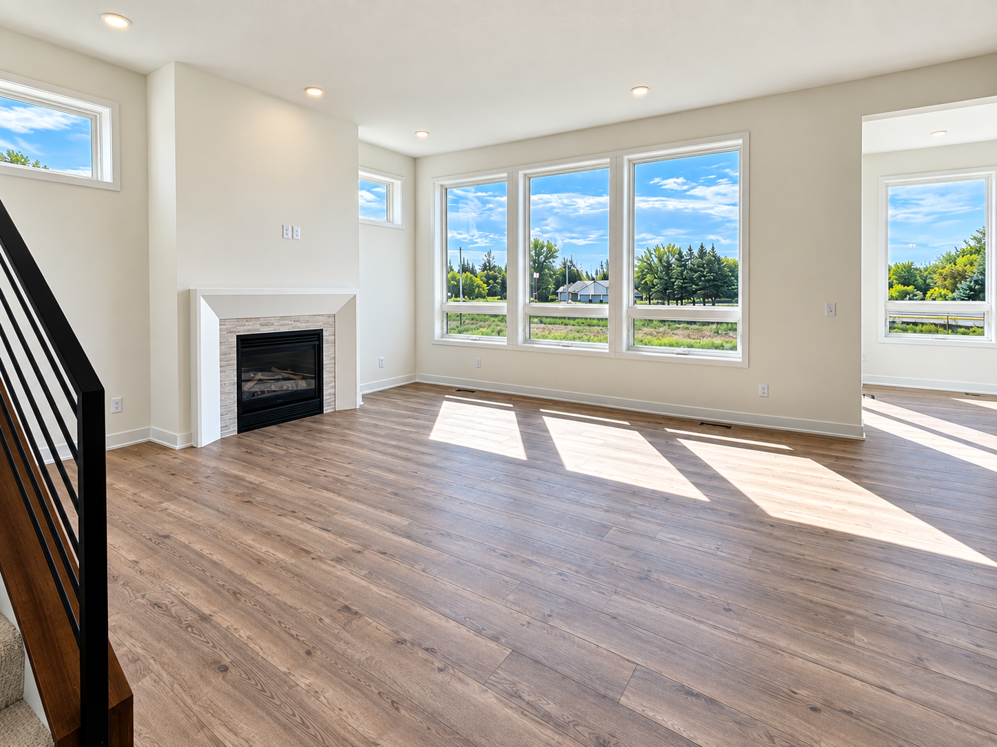 Spacious great room with abundant natural light, modern fireplace, and large windows showcasing the surrounding views.