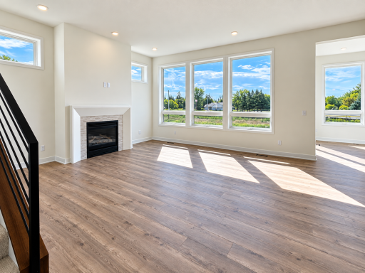Spacious great room with abundant natural light, modern fireplace, and large windows showcasing the surrounding views.