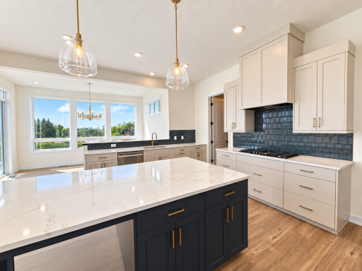 Open-concept kitchen and dining area filled with natural light, featuring an oversized island, abundant cabinetry, and expansive windows.