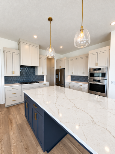 Beautifully appointed kitchen with contrasting island cabinetry, quartz countertops, statement backsplash, gas cooktop, and extensive storage.