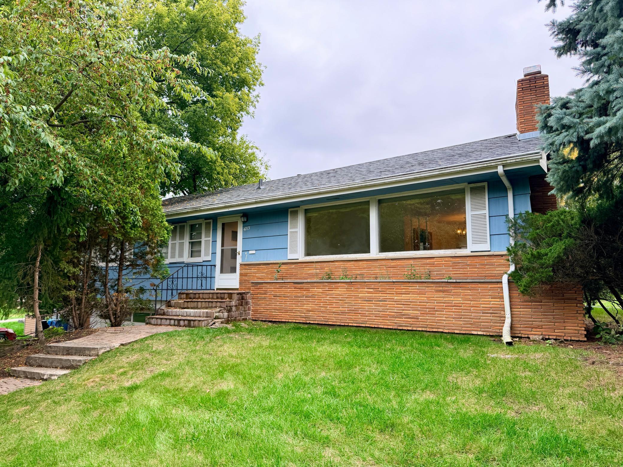 This one-story home has authentic 1950s mid-century features including brick wainscoting on the front facade and oversized front windows.