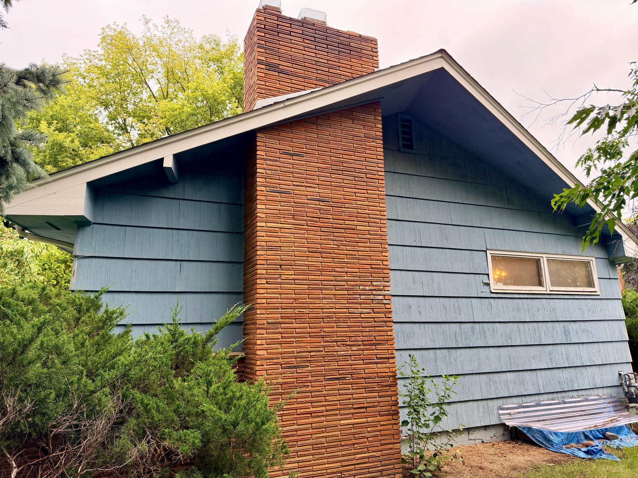 The mid-century oversized eave accentuates the large brick chimney that runs the height of the main level.