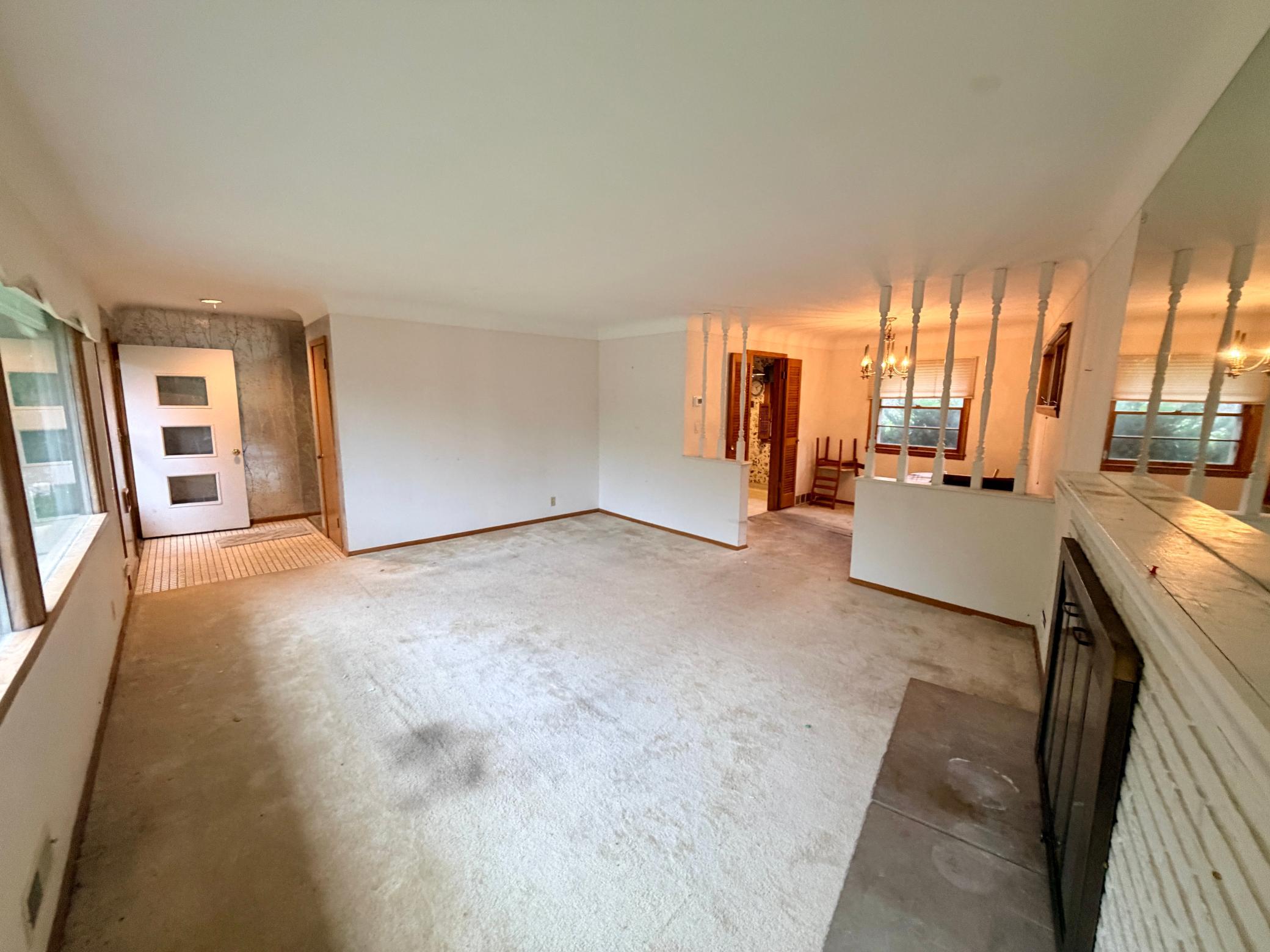 The bright and open main level living room has oversized windows with easy flow. The focal point is the mid-century fireplace with period-specific brick work. The decorative pony wall provides openness while defining the spaces.