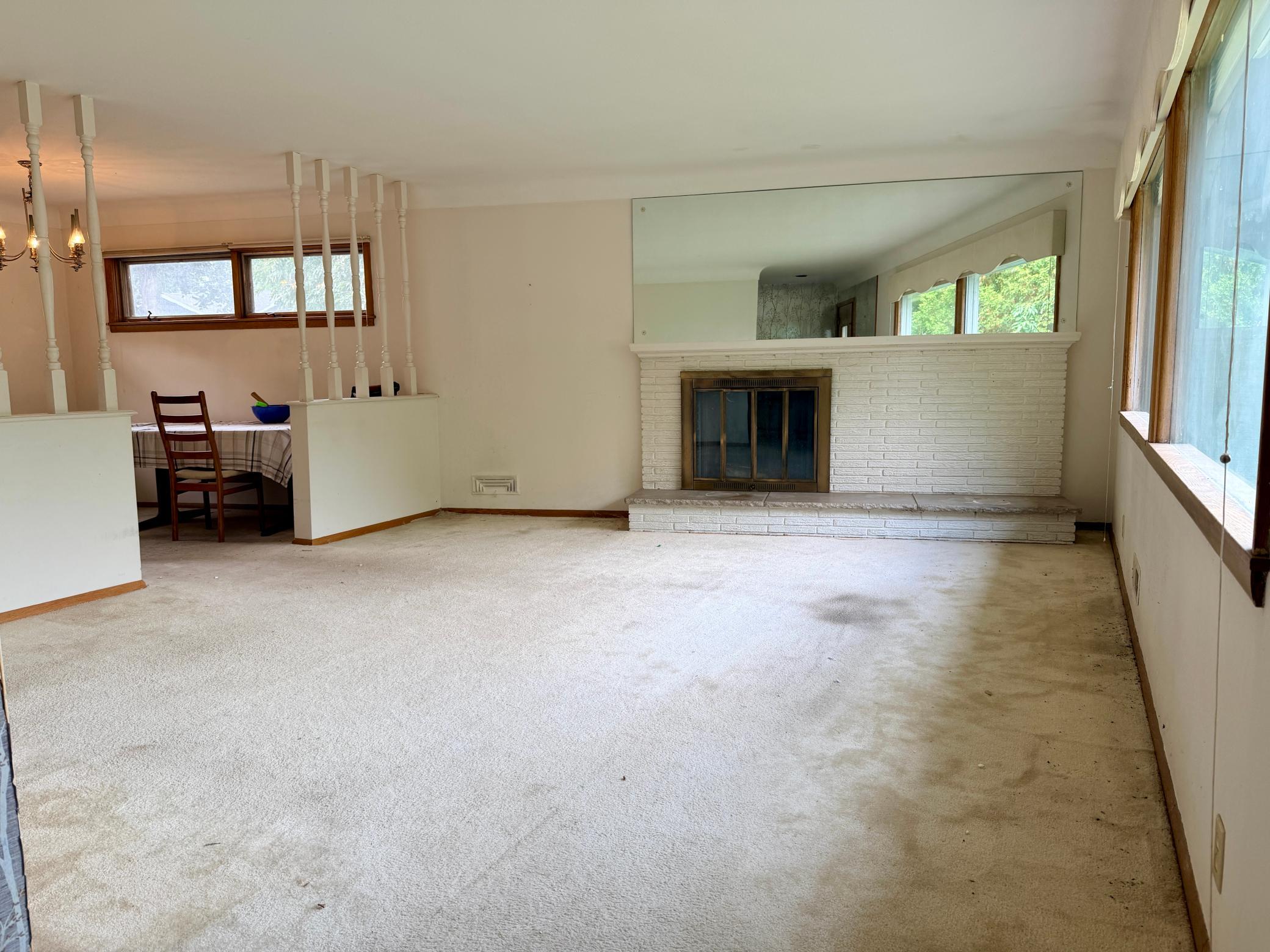 The focal point of the bright, main level living room is the wood-burning, mid-century offset fireplace with period-specific brick work and hearth.