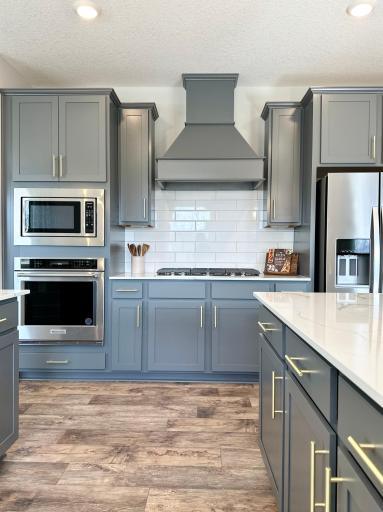 Beautiful and on trend, greyhound cabinets with quartz countertops and tile backsplash. Soft close drawers and pull out garbage/recycle center included! Photo of model home, colors and finishes vary.