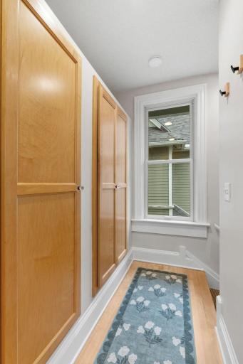 Hallway with deep storage cabinets leads to back entryway to condo