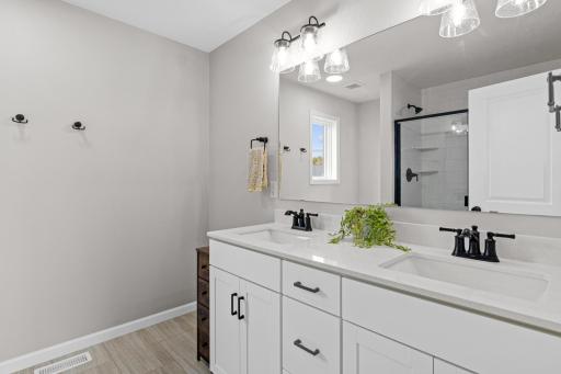 Owners bathroom with dual sinks and 3/4 shower with door and tilework