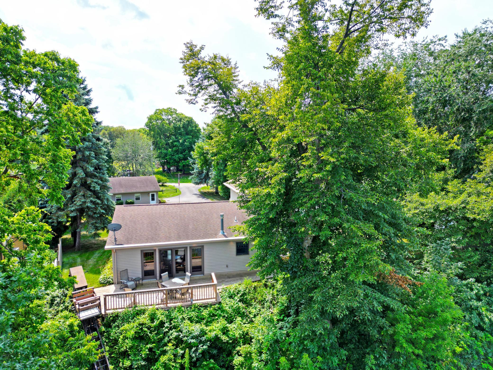 The lakeside of the home is surrounded by mature trees, creating a private setting with a spacious deck overlooking the lake.