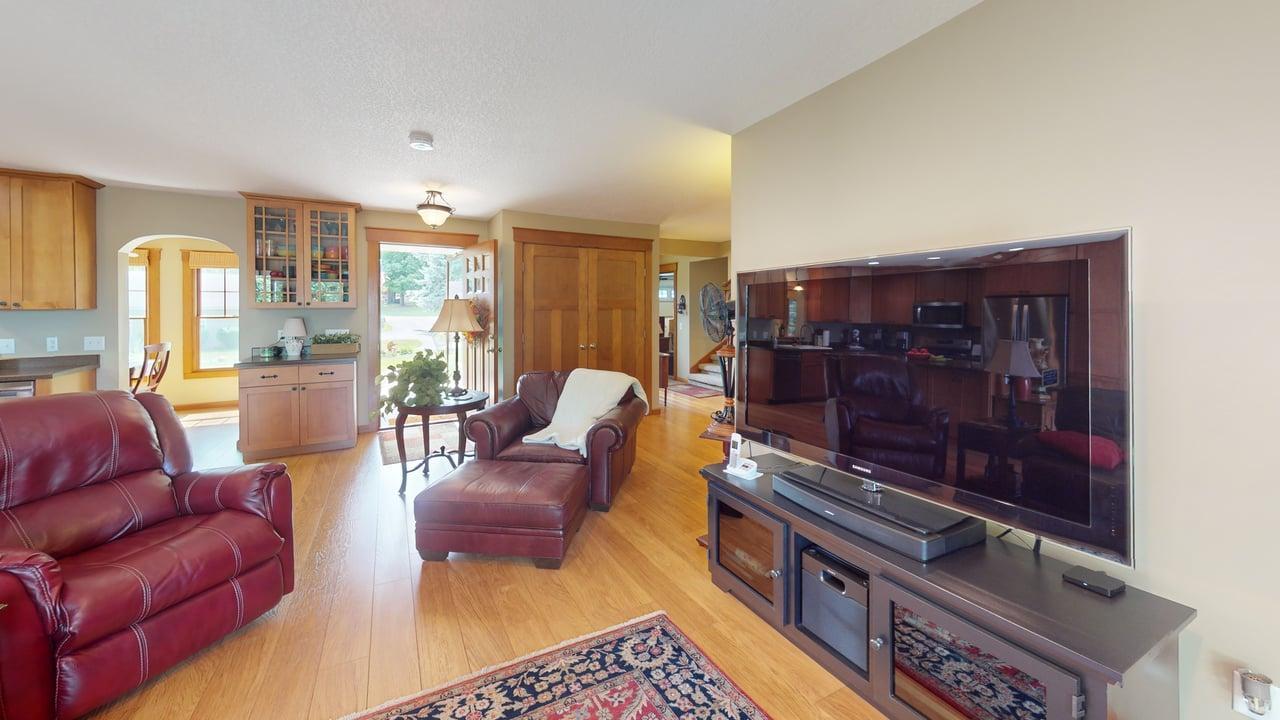Spacious living room with warm hardwood floors and an open layout that flows easily into the kitchen and dining areas.