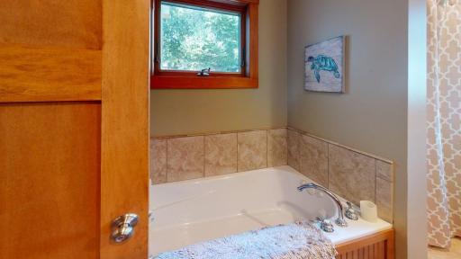 Main-level full bathroom features a relaxing jetted tub surrounded by tile and a window bringing in fantastic natural light.