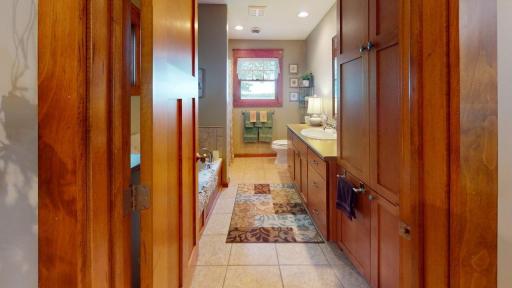 Spacious full bathroom offers a long vanity with plenty of cabinetry and counter space, along with a jetted tub and shower.