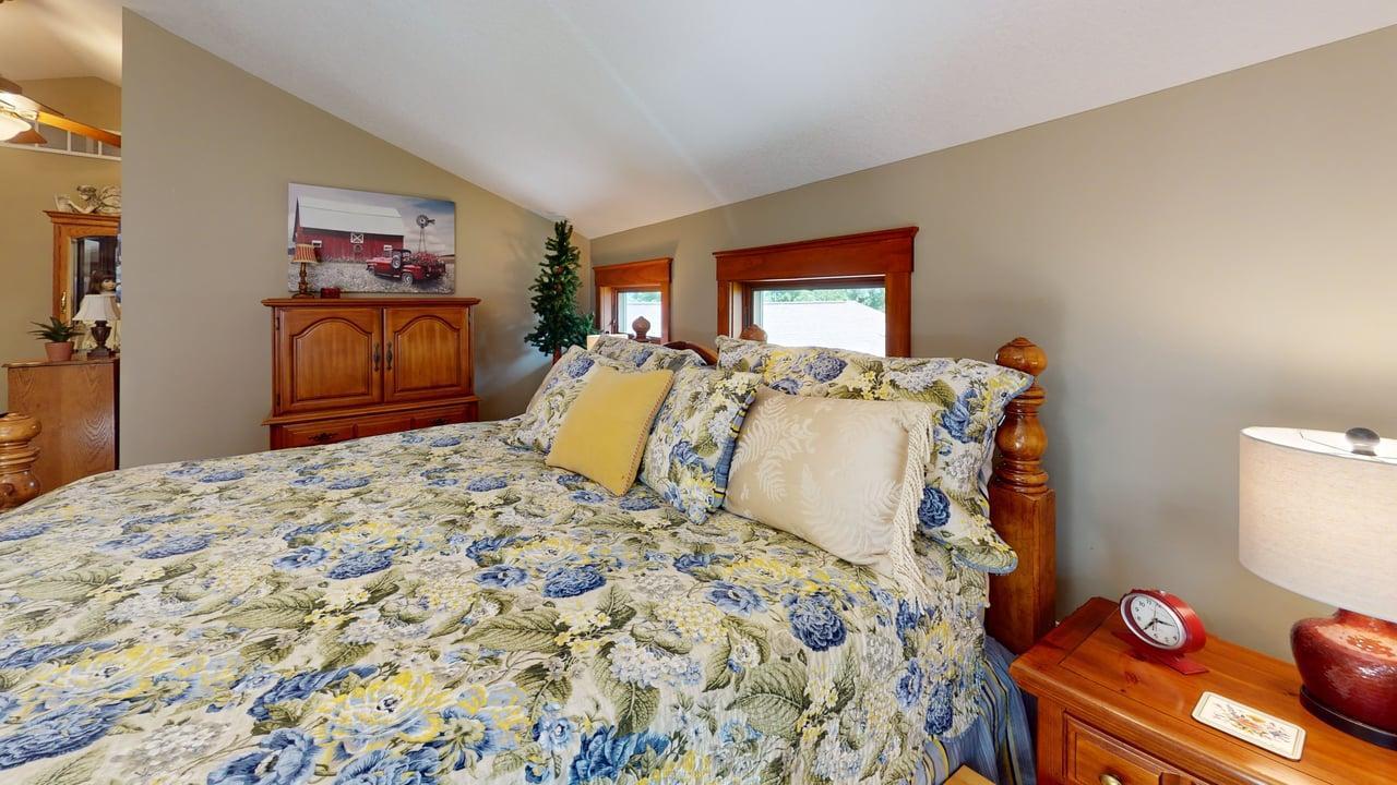 Large comfortable upper-level bedroom with vaulted ceilings and charming windows that bring in plenty of natural light.
