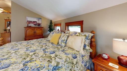 Large comfortable upper-level bedroom with vaulted ceilings and charming windows that bring in plenty of natural light.