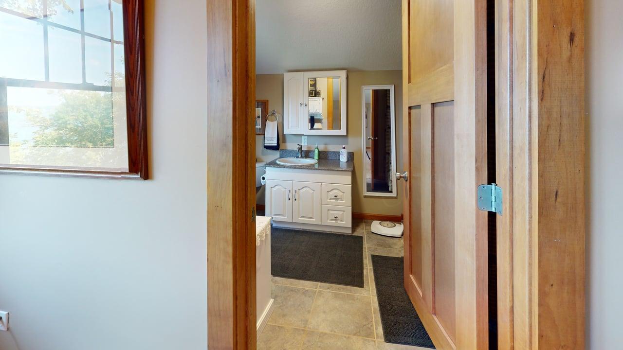 Upper-level three-quarter bathroom offers a convenient vanity area, mission-style doors, tiled flooring and plenty of natural light.