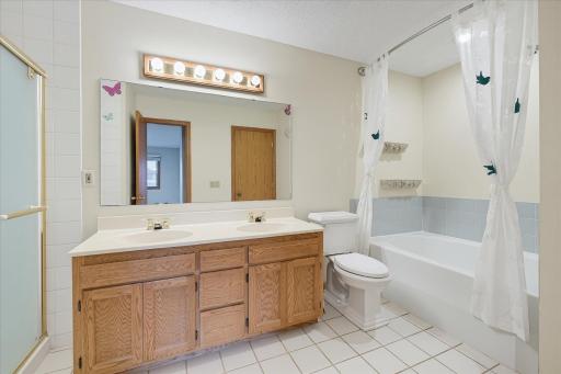 Main level full bath features a double vanity, walk in shower, and separate soaking tub