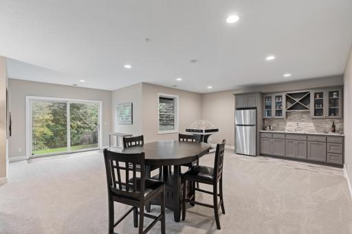 Open lower-level great room offering flexible use as a dining area or game room, with walkout access to the private backyard.